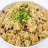 A colorful dish of Mediterranean Roasted Eggplant and Raisin Couscous with Toasted Pine Nuts, showcasing golden couscous, deep purple eggplant, glistening raisins, and golden-brown pine nuts, garnished with fresh green herbs.