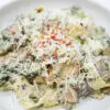 A plate of Creamy Spinach and Wild Mushroom Pappardelle, showcasing wide ribbons of pasta coated in a rich, creamy sauce with vibrant green spinach and golden-brown mushrooms, sprinkled with red pepper flakes for a touch of warmth.