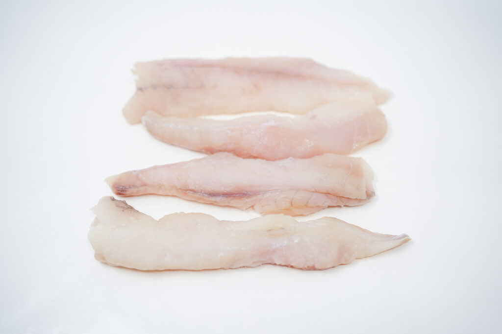 Raw monkfish fillets on a clean white background, showcasing their firm, white flesh with a slightly translucent appearance.