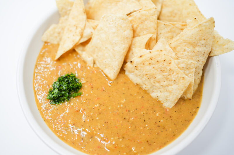 A bowl of vibrant Bell Pepper Salsa Verde, featuring roasted tomatillos and bell peppers, garnished with fresh cilantro, surrounded by crispy tortilla chips.