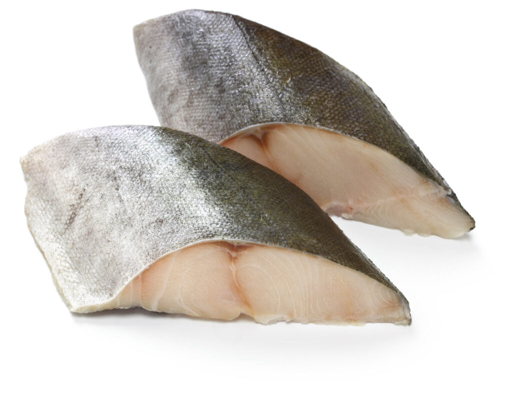 Raw black cod fillets with skin on, displayed on a white background.