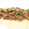 A plate of Ground Beef and Mushroom Duxelles Tacos filled with savory beef and mushroom mixture, topped with vibrant roasted tomato and pasilla pepper salsa, garnished with fresh cilantro, and served with lime wedges on warm flour tortillas.