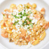 A bowl of Creamy Shrimp, White Corn, and Chipotle Gnocchi featuring tender shrimp, sweet corn, and gnocchi in a rich cream sauce, garnished with fresh basil and crumbled queso fresco.
